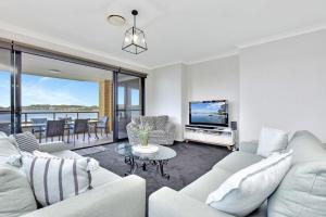 a living room with a couch and a tv at Water's Edge Apartment 2 absolute waterfront at Fishing Point on Lake Macquarie in Fishing Point