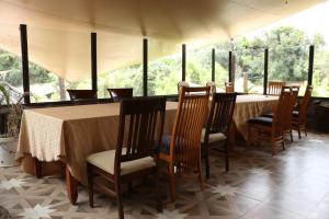 comedor con mesa, sillas y ventanas en Brooks Lodge, en Nakuru