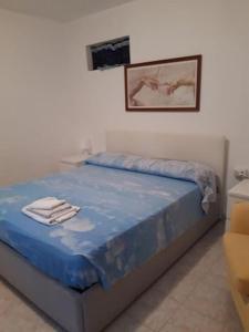a bed with a blue blanket and a picture on the wall at Villa Patty in Pian di Mulino