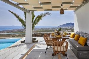 un patio con mesa, sillas y piscina en El Verano Hideaway, en Imerovigli