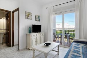 een witte woonkamer met een televisie en een tafel bij Casa María in Conil de la Frontera