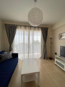 ein Wohnzimmer mit einem blauen Sofa und einem TV in der Unterkunft Hills&Seaview in Peyia