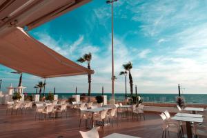 a patio with tables and chairs and the ocean at Hotel Vértice Chipiona Mar in Chipiona