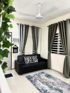 um sofá preto numa sala de estar com cortinas em DeAsmarra Homestay em Tanjung Piandang