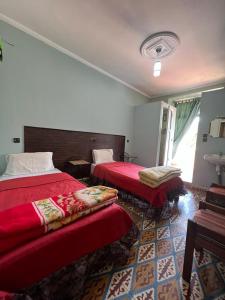 una camera d'albergo con due letti con lenzuola rosse di Hotel des cedres,azrou maroc ad Azrou