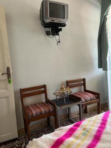 Habitación con 2 sillas, mesa y TV. en Hotel des cedres,azrou maroc en Azrou