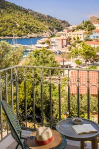 a table with a hat and a glass of wine on a balcony at Chromata Assos Villas Kefalonia in Asos