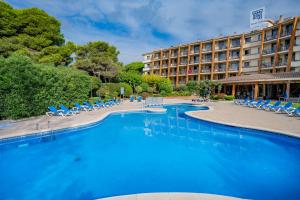 un complejo con una gran piscina con tumbonas en GHT Aparthotel Tossa Park en Tossa de Mar