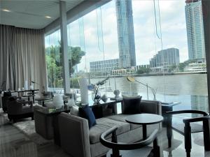 a living room with a couch and tables and a large window at Luxury River View in Bangkok