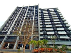 een hoog gebouw met palmbomen ervoor bij Haiyu Island Spring Apartment in Toucheng