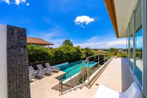 an outdoor deck with chairs and a swimming pool on a house at Phu Montra Villa with Ocean View in Khao Tao