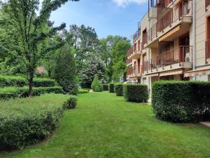 a yard in front of a building with bushes at Sunny Apartman in Siófok