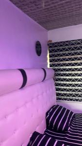 a purple room with a bed and a pillow at Tommy’s place in Iki