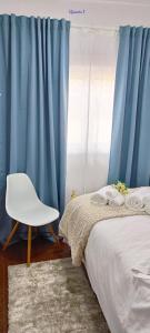 a bedroom with blue curtains and a chair next to a bed at Casa Sardinha 