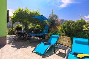 a patio with blue chairs and a table at House Zrile with garden and jacuzzi in Baška