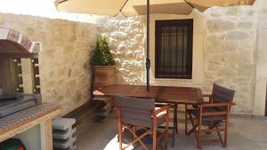 a wooden table and chairs under an umbrella at Amazing Stone Villas in Kapetanianá