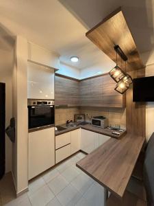 une cuisine avec des placards blancs et un comptoir en bois dans l'établissement Apartmani Matic 6, à Jagodina