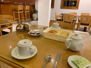 einen Tisch mit Tassen und Untertassen darüber in der Unterkunft De La Plaza Hotel in Villa Gesell