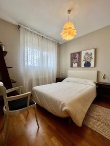 ein Schlafzimmer mit einem Bett, einem Stuhl und einem Fenster in der Unterkunft Ático 360º de Burgos ATUAIRE in Burgos
