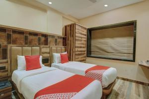 two beds in a room with red and white at Laxman Residency in Kulurkudrū