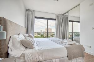 Un dormitorio con una cama blanca con una ventana grande. en Live Soho Boutique Apartments Belgrano, en Buenos Aires