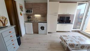 małą kuchnię z białymi szafkami, pralką i suszarką w obiekcie Studio à 50 m de la plage et du sentier littoral w Hyères