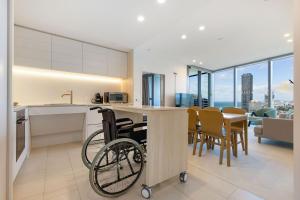 a wheelchair in a kitchen with a table and chairs at ULTIQA Signature at Broadbeach in Gold Coast