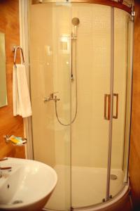 a shower with a glass door next to a sink at Sapar Budget Hotel in Shymkent