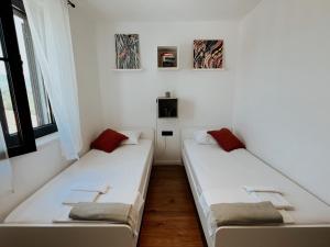 two beds in a room with white walls and windows at Dawn & Dusk - Modern Two Bedroom Apartment with Mountain Views in Čilipi