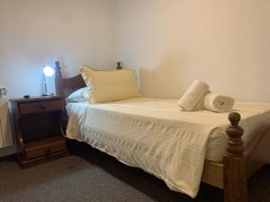 a bed with white sheets and pillows on it at De La Plaza Hotel in Villa Gesell