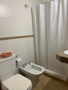 a bathroom with a toilet and a shower and a sink at De La Plaza Hotel in Villa Gesell