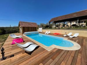 a swimming pool on a wooden deck with chairs around it at Le Clos Des Buis Gîte de Charme AZUL in Cazals