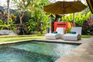 um guarda-sol e cadeiras junto a uma piscina em Romantica Villa Ubud em Ubud