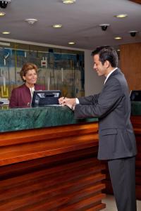 a man in a suit standing at a cash register at Marriott Venezuela Hotel Playa Grande in Playa Grande