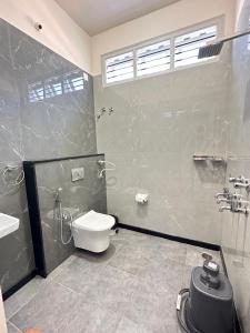 a bathroom with a toilet and a shower and a sink at Anthara Service Apartment in Belūr