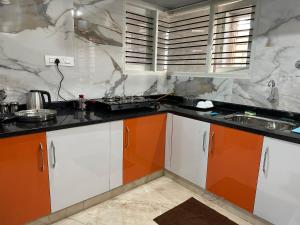 a kitchen with orange and white cabinets and a stove at Anthara Service Apartment in Belūr