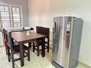 a kitchen with a table and a stainless steel refrigerator at Anthara Service Apartment in Belūr