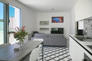 cocina y sala de estar con sofá y mesa en Perle Marine Suite Apartments, en Castro di Lecce