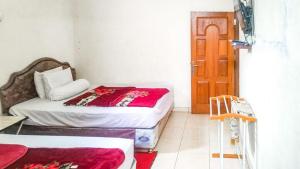 a bedroom with two beds and a wooden door at Villa Al Barokah Syariah Family Mitra RedDoorz near Sarangan Lake in Sarangan