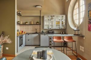 a kitchen with white cabinets and a table at Màrita Apartment in Lucca