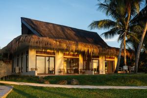 una casa con techo de paja y palmeras en Costa Celine Beach Resort en Kinablañgan