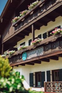 ein Gebäude mit Blumen auf den Balkonen und ein Willkommensschild in der Unterkunft Wiefarn Apartments - Ferienwohnungen in Bad Wiessee am Tegernsee in Bad Wiessee