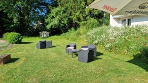 een groep stoelen en een paraplu in het gras bij Seehotel in Kell