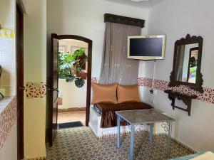 a living room with a couch and a tv on the wall at Riad Salt River in Martil