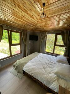 Bizim O'ra Küme Evleri & Bungalov في طرابزون: غرفة نوم مع سرير في غرفة مع نوافذ