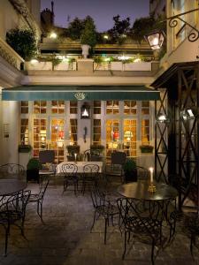 un patio al aire libre con mesas y sillas por la noche en Hôtel Duc De St-Simon, en París