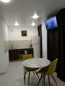 a kitchen with a table and yellow chairs and a tv at Студія зі Смарт ТВ,кондиціонером in Kryvyi Rih
