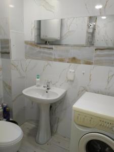 a white bathroom with a sink and a washing machine at Студія зі Смарт ТВ,кондиціонером in Kryvyi Rih
