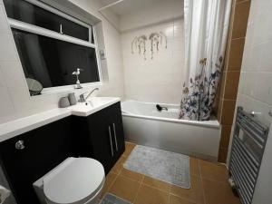 e bagno con servizi igienici, lavandino e vasca. di Charming 4-Bed House in Cheltenham Free Parking a Cheltenham