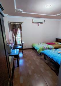 een kamer met 2 bedden, een tafel en een raam bij Hotel Bima in Klaten